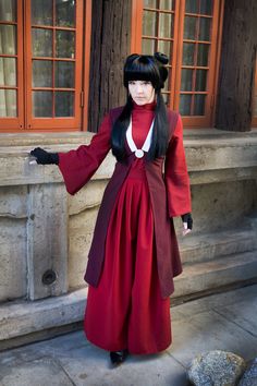 a woman dressed in red and black standing next to a building