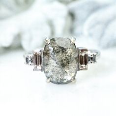 a close up of a ring with a stone in the middle and two diamonds on each side