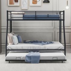 a bunk bed with two mattresses underneath it in a white room next to pictures on the wall