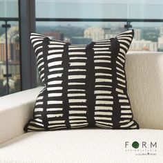 a black and white striped pillow sitting on top of a couch next to a window