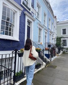 a woman is walking down the sidewalk in front of some blue and white houses,