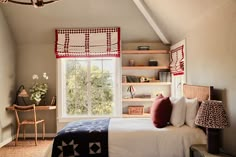 a bed sitting under a window next to a wooden shelf filled with books on top of it