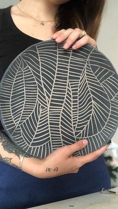 a woman holding a plate with designs on it