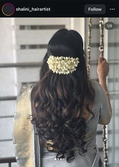 the back of a woman's head with long hair and flowers in her hair