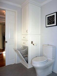 a white toilet sitting inside of a bathroom next to a wall mounted cabinet with an open door