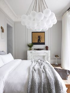 a bedroom with white bedding and a chandelier hanging from the ceiling