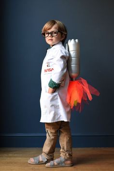 a little boy dressed up as a chef holding a canister and an orange flower