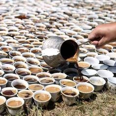 someone is pouring coffee into cups on the ground