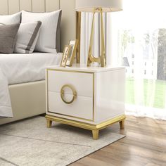 a white and gold nightstand sitting on top of a wooden floor next to a bed