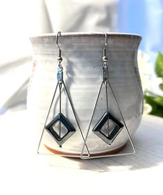 These fun earrings are made with a silver plated triangle and a hematite diamond shape that dangles from the top of the triangle. They dangle about two inches from the stainless steel ear wire. Modern Silver Triangle Earrings, Modern Nickel-free Triangle Earrings, Nickel Free Triangle Metal Earrings, Nickel-free Metal Triangle Earrings, Silver Triangle Jewelry With Ear Wire, Earring Frame, Earrings Triangle, The Triangle, Triangle Earrings