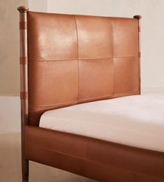 a brown leather bed frame with white sheets