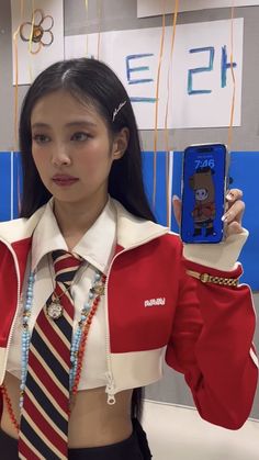 a girl in a school uniform holding up her cell phone