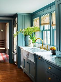 a kitchen with blue cabinets and marble counter tops in the center, along with a striped rug on the floor