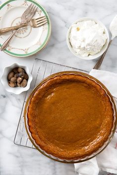 a pie sitting on top of a white table next to plates and silver utensils