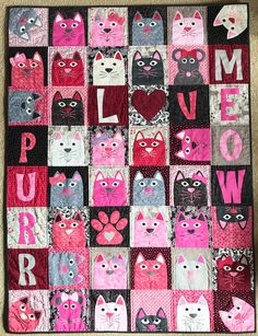 a quilt made to look like cats with the word love spelled in pink and black