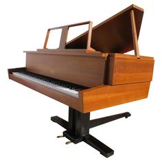 an old wooden piano sitting on top of a black stand