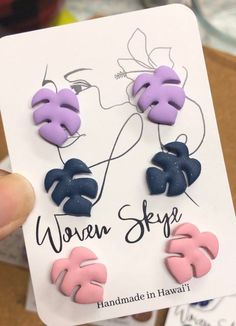 a pair of purple and blue earrings with monster leaves on the back of each ear