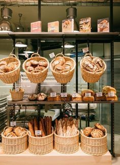 breads and pastries are displayed in baskets on the shelves at a baker's