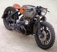 an old motorcycle is parked on the ground in front of some concrete and dirt flooring