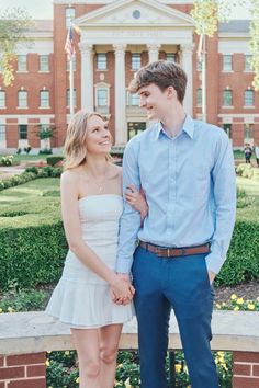 a young man and woman standing next to each other in front of a building