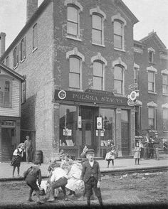 an old black and white photo of children playing in front of a building with people standing outside