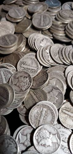 a pile of silver coins sitting next to each other on top of a black table