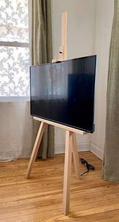 a flat screen tv sitting on top of a wooden stand in front of a window