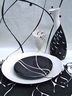 a black and white table setting with two vases on the left, an empty plate on the right