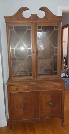 an old wooden china cabinet with glass doors on the top and bottom, in a living room