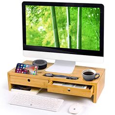 a computer desk with a keyboard, mouse and cell phone on it in front of a monitor