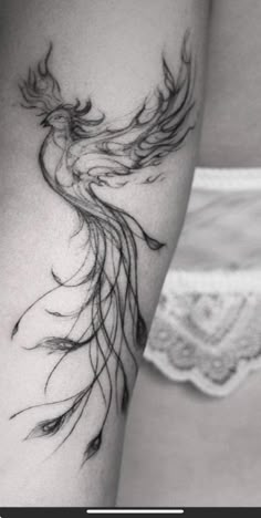 black and white photo of a woman's arm with a bird tattoo on it