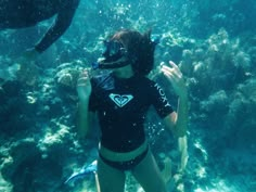 a woman wearing a diving mask and snorkels in the water near a coral reef