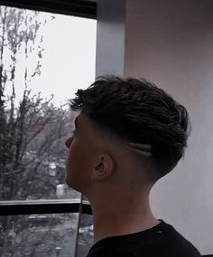 a young man with black hair looking out the window