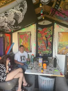 two people sitting at a table with art on the walls