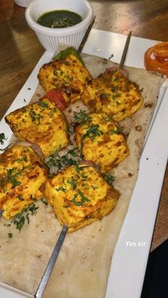 several square pieces of tofu on a plate with a knife and bowl of dipping sauce