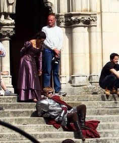 some people are sitting on the steps and one is wearing a purple dress with silver accents