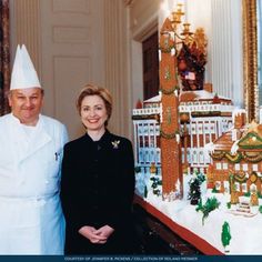 two people standing next to each other in front of a ginger - themed building and clock tower