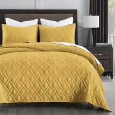 a bed with yellow bedspread and white pillows