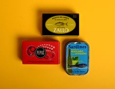 two tins of soap sitting next to each other on a yellow surface