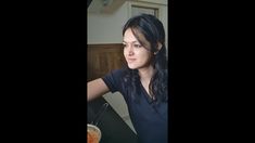 a woman sitting at a table with a bowl of food in front of her and looking off into the distance