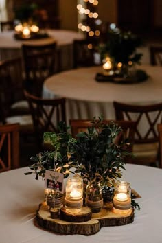 candles are lit in mason jars on top of a wooden slice that is sitting on a table