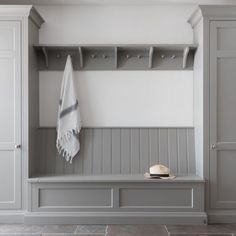 a white hat is sitting on a bench next to a gray coat rack and some shelves