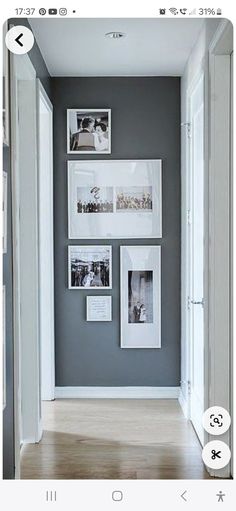 a hallway with pictures on the wall and wooden floors in front of an open door