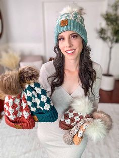 a woman is holding two knitted mittens