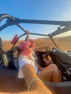 a woman is sitting in the driver's seat of a dune buggy with her feet on the steering wheel