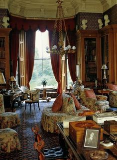 a living room filled with lots of furniture next to a large window covered in curtains