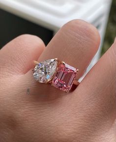 a close up of a person's hand with a pink and white diamond ring