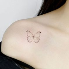 a small butterfly tattoo on the back of a woman's left shoulder is shown