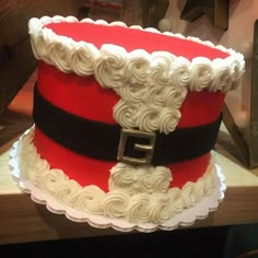 a red and white cake with santa claus hat on it's top, sitting on a table