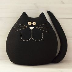 a black cat purse sitting on top of a white wooden floor next to a wall